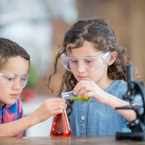 school age child holding beaker while another school age child pours liquid