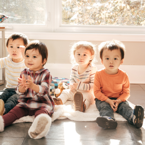 four toddlers sitting on floor facing forward