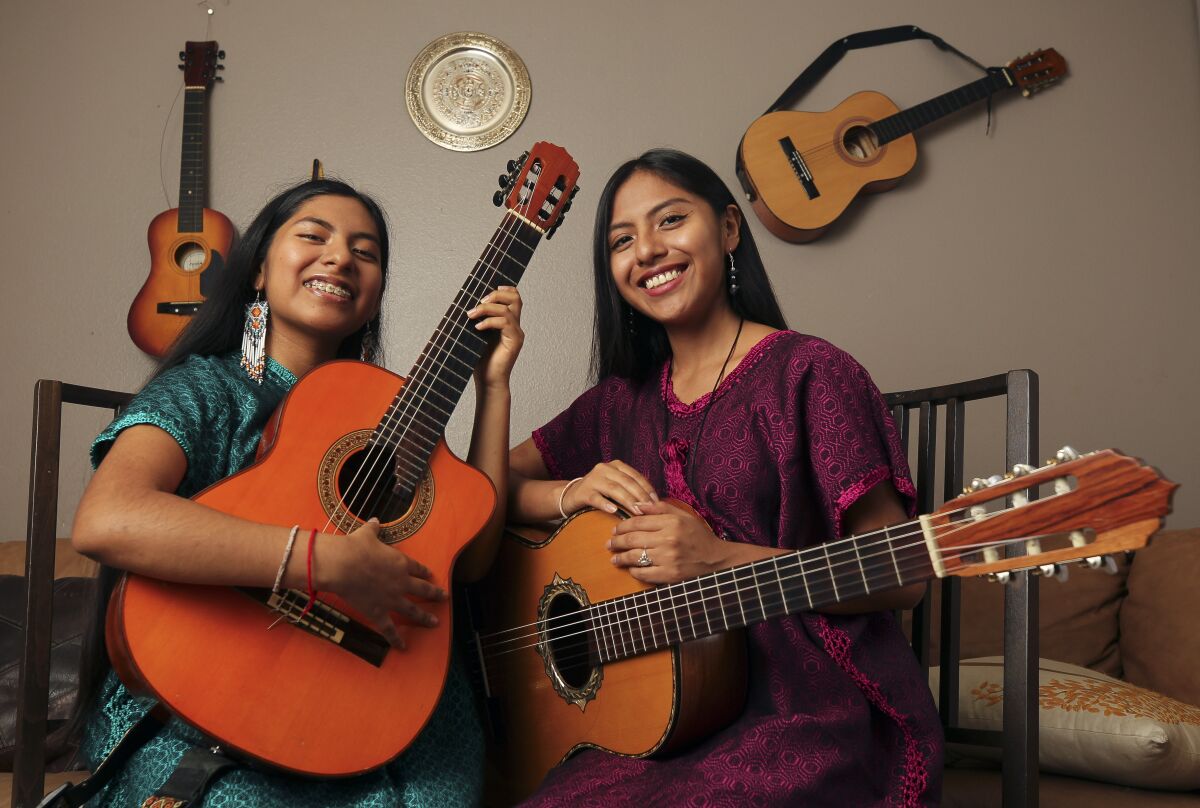 Two women musicians holding a guitar