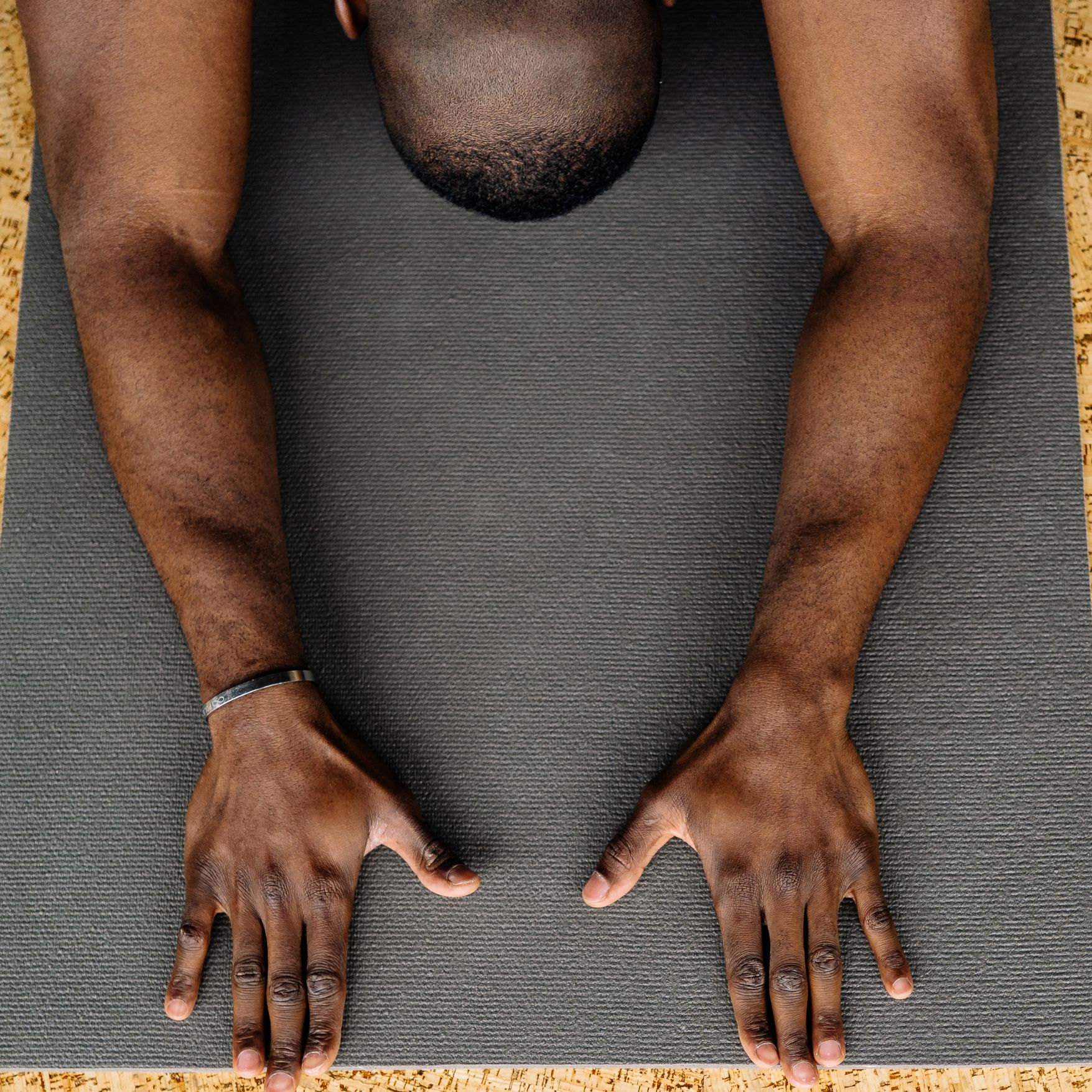Hands of Black man on grey yoga mat in child's pose