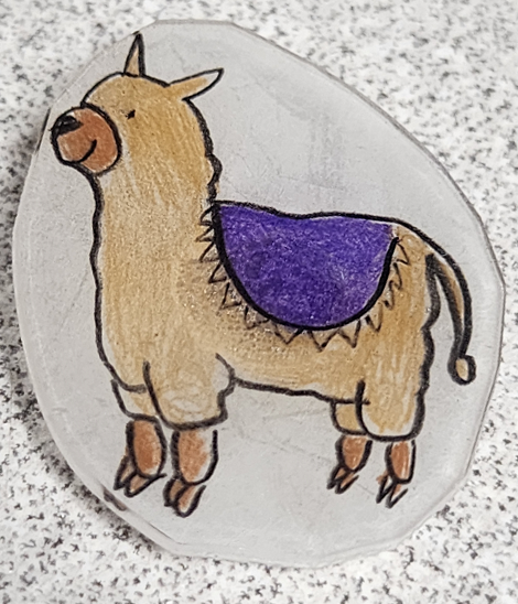Small cute llama fridge magnet. The llama is wearing a purple blanket.