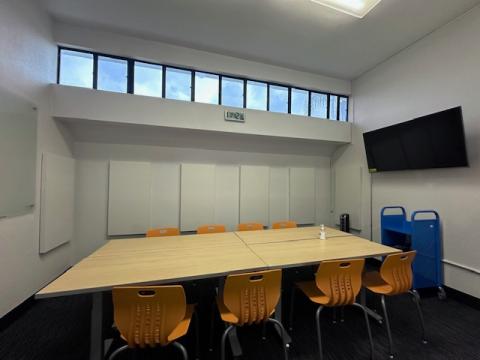 Enclosed study room with two tables and eight chairs with small windows up above