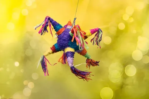 Colorful piñata swinging in a yellow background 
