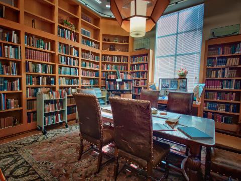 Old books on wooden shelves, wooden table, and leather chairs.