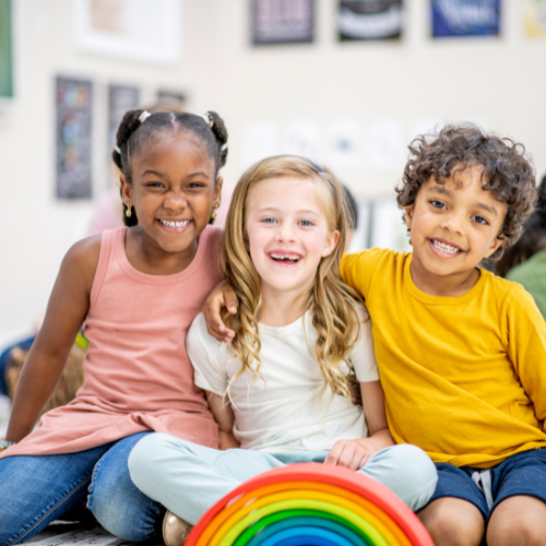 three smiling children sitting on ground