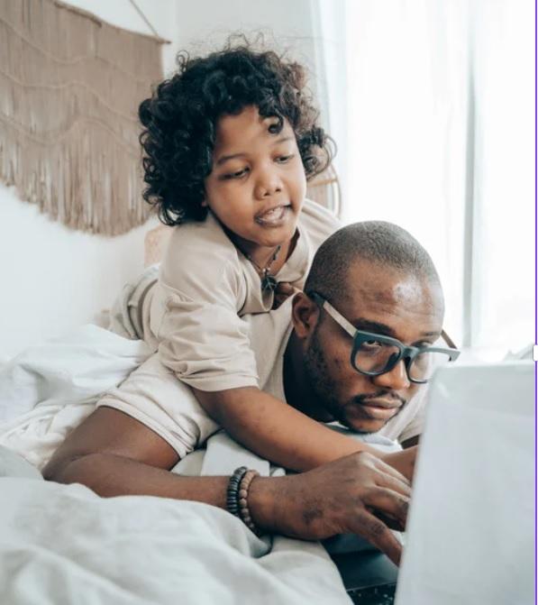 Child leaning over father looking at computer