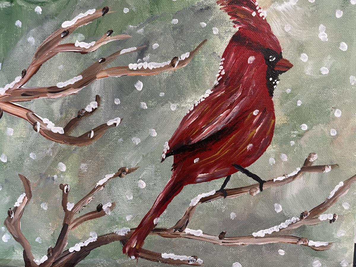 Red cardinal bird on a branch with snow falling.